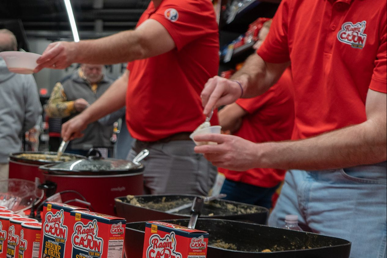 Acadian Kitchens team members cooking outdoors in Raginâ Cajun shirts