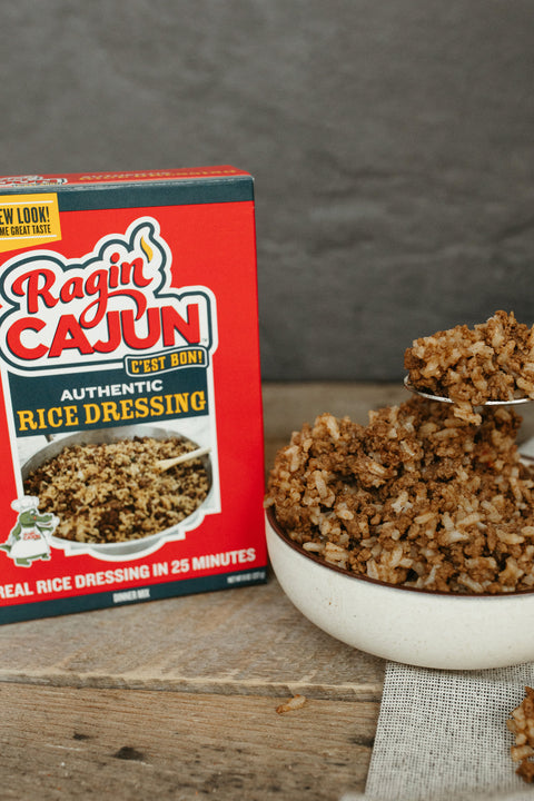 Box of Ragin Cajun rice dressing next to a bowl of rice with a spoonful of dressing.