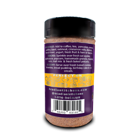 Product photography by Acadian Kitchens of a "Perfect On" seasoning blend jar featuring a dark purple label with white text detailing breakfast, snack, and dessert uses, a gold band showcasing silver food icons like a coffee cup, pancakes, and strawberry, and a visible barcode on a white background
