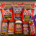 A Flavors of New Orleans Variety Pack in a cardboard box featuring prominent red and purple Ragin' Cajun and Cajun's Choice product packaging including Jambalaya mix, Seasoned Red Beans, and Authentic Creole Sauce, highlighted by red fleur-de-lis graphics