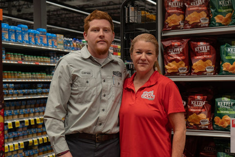 Two people standing in a grocery store aisle with Kettle Chips on shelves behind them.
