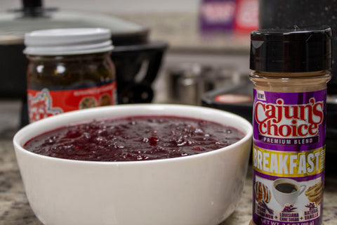Bowl of jam with a jar of Cajun's Choice seasoning on a kitchen counter.