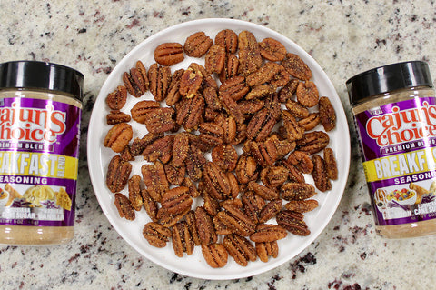 Spiced pecans on a plate with Cajun's Choice seasoning containers.