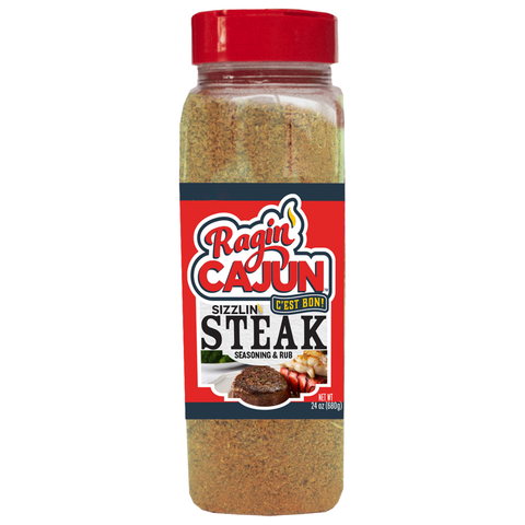 Product photography of a Ragin' Cajun Sizzlin' Steak Seasoning & Rub bottle, a clear plastic container with a red flip-top cap and a bold red label featuring "Ragin' Cajun" in stylized script, a yellow "C'EST BON!" speech bubble, and an image of a cooked steak and lobster tail