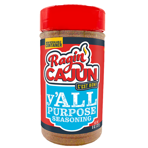 Product photography of a Ragin' Cajun Y'all Purpose Seasoning bottle featuring a bright red lid, a vibrant red and blue label with "Ragin' Cajun" text, a yellow flame graphic, and the slogan "C'EST BON" on a black banner