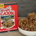 Box of Ragin Cajun rice dressing next to a bowl of rice cake on a wooden surface.