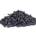 A pile of dried black beans with visible white hilums against a clean white background