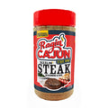 Ragin' Cajun Sizzlin' Steak Seasoning & Rub 8 oz bottle against a white background, featuring a vibrant red cap, the C'est Bon! flame logo, and illustrations of a grilled steak and lobster on its label
